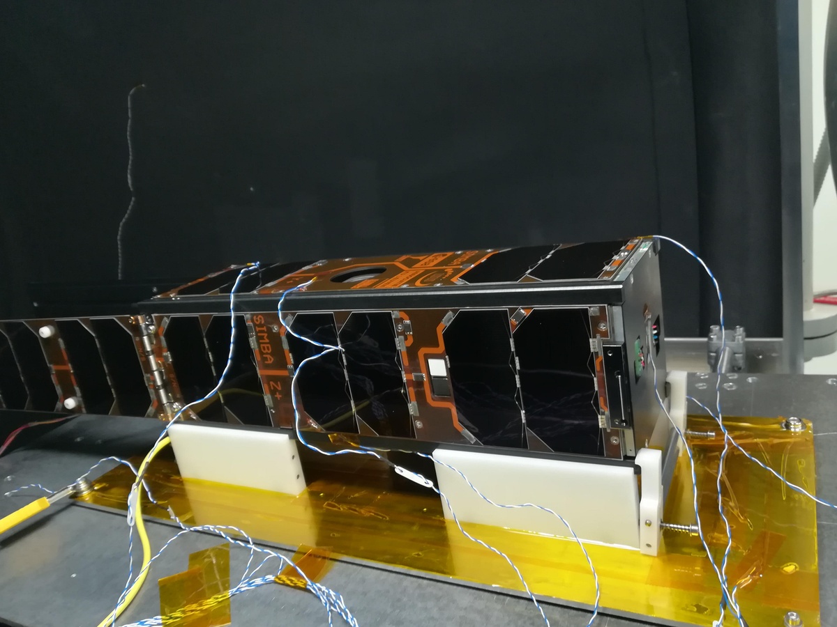 SIMBA prêt à être testé dans la chambre thermique sous vide. La partie arrière du satellite est visible ainsi que les panneaux solaires et deux senseurs spectroscopiques. Les câbles sont reliés à des thermocouples afin de surveiller la température du satellite pendant les tests.